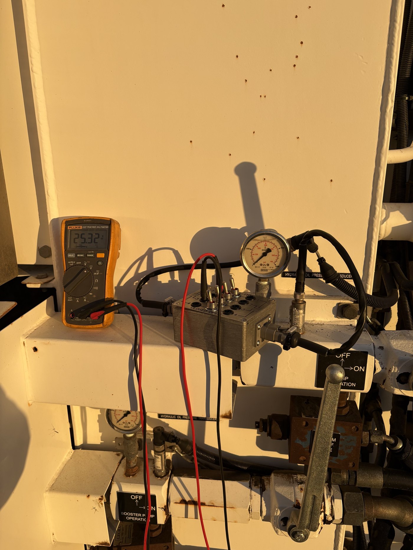 ACCER Sensor Test Box connected on heavy equipment with a multimeter displaying 25.32 volts